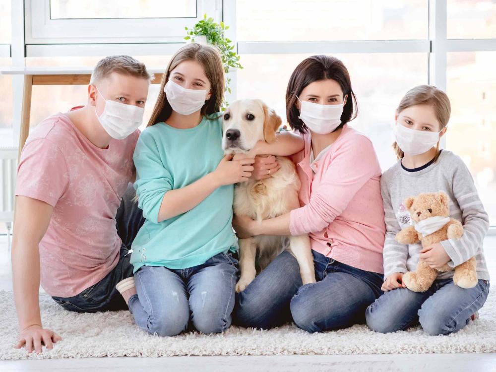 parents, two children, dog and doll, all wearing masks