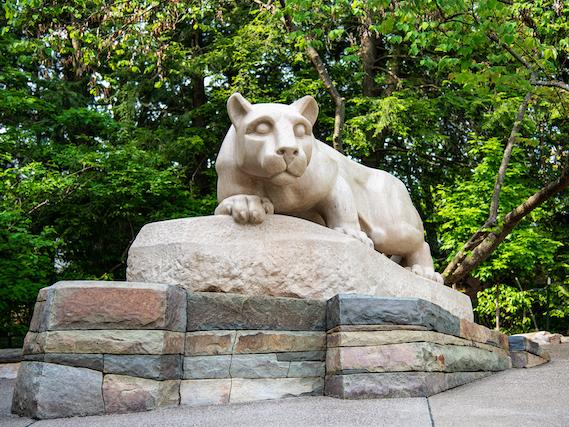 A statue in the shape of a mountain lion sitting atop rocks