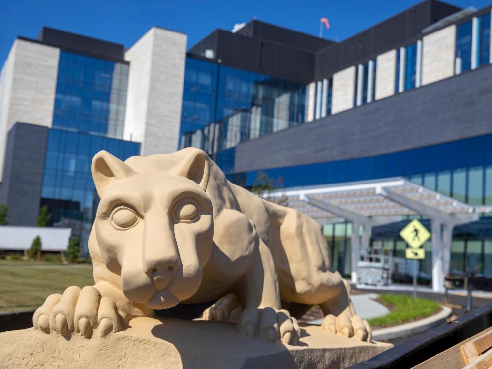 A photo of the Nittany Lion statue in front of a hospital
