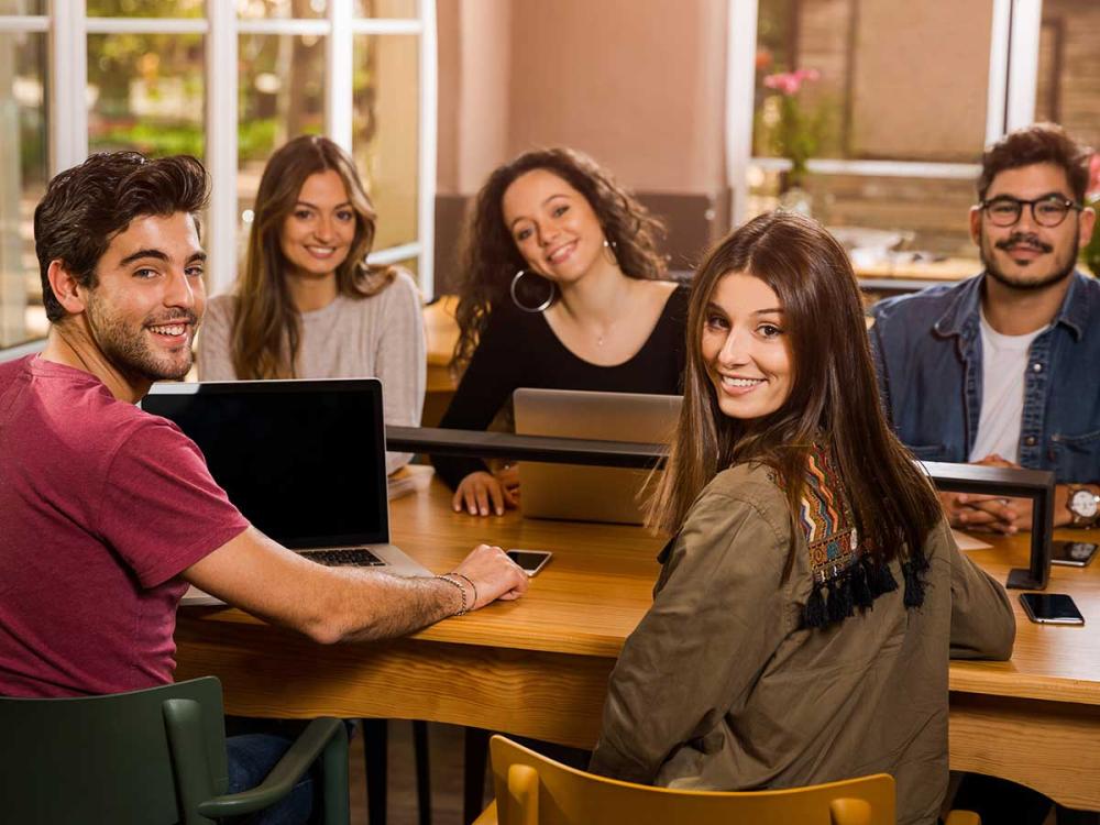 group of smiling college students sitting at table