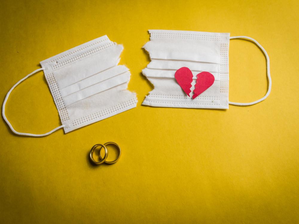 A white medical face mask cut in half with a broken heart on one side