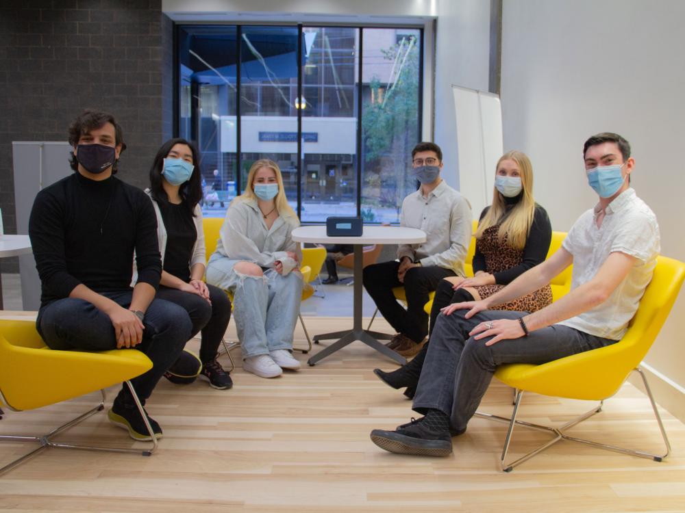 students sit in yellow chairs in office