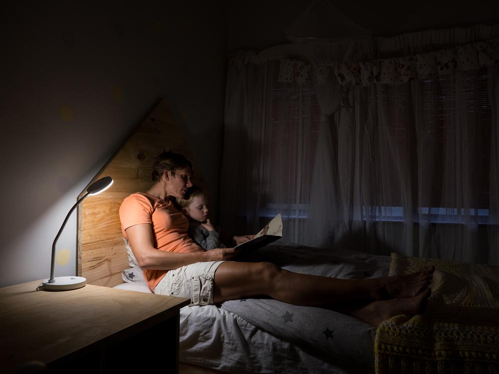 A mother reading to her daughter in bed at night.