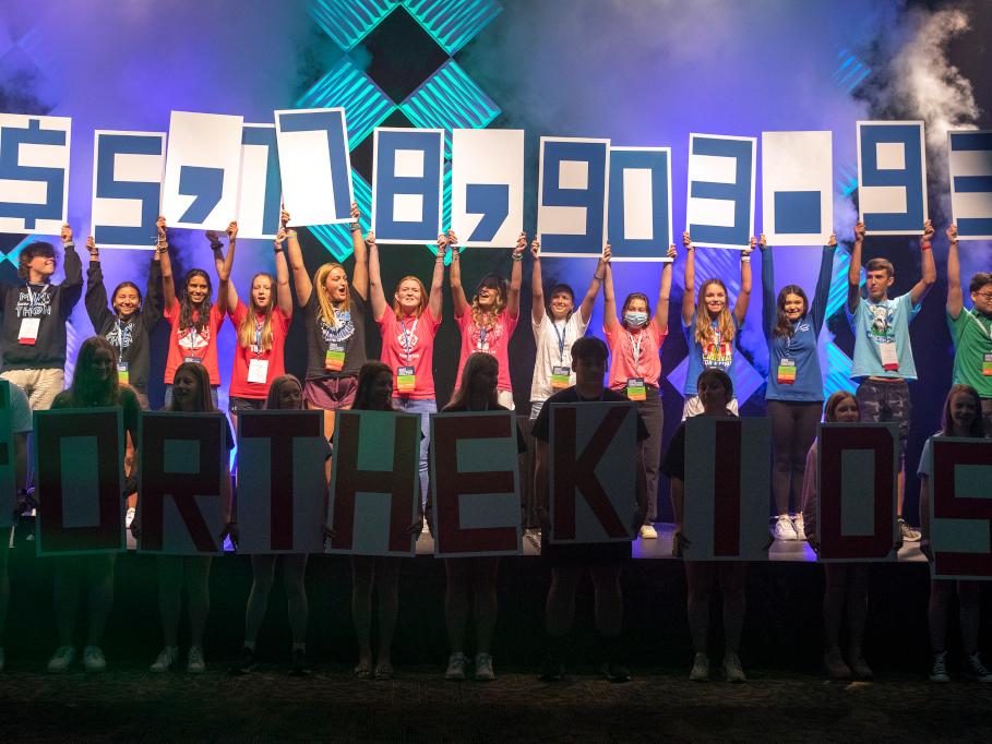 Students hold up signs with numbers on them to reveal a fundraising total of more than $5.7 million