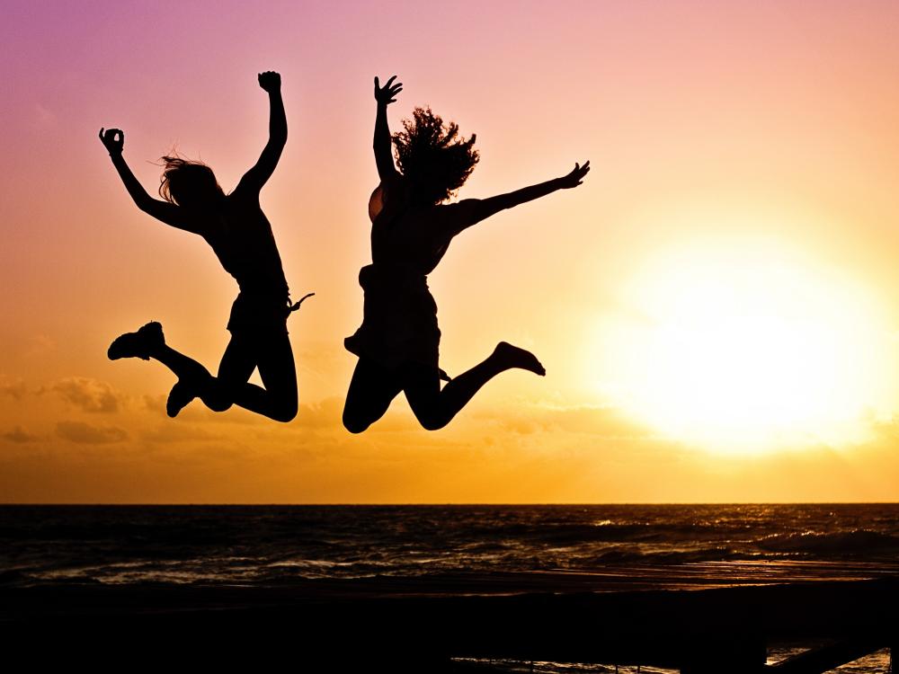 Two People Jumping In Front of a Sunset