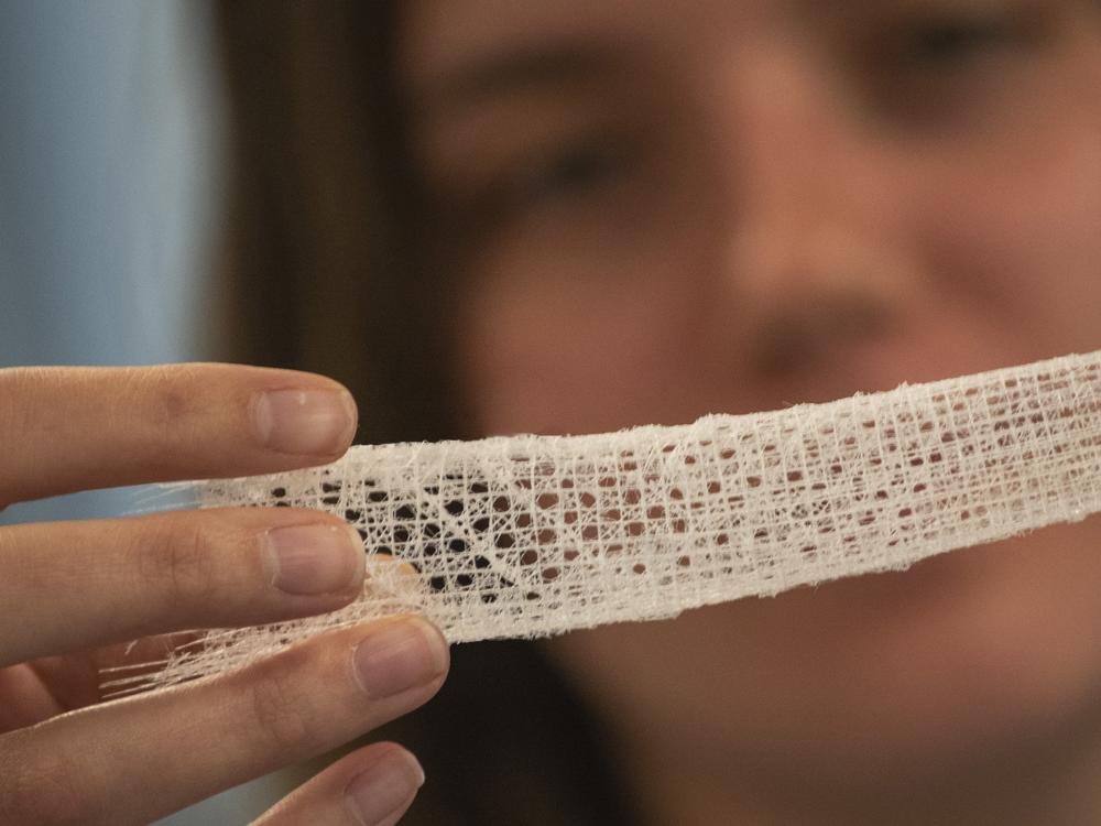 Woman out of focus in background looking at a closeup of a sample