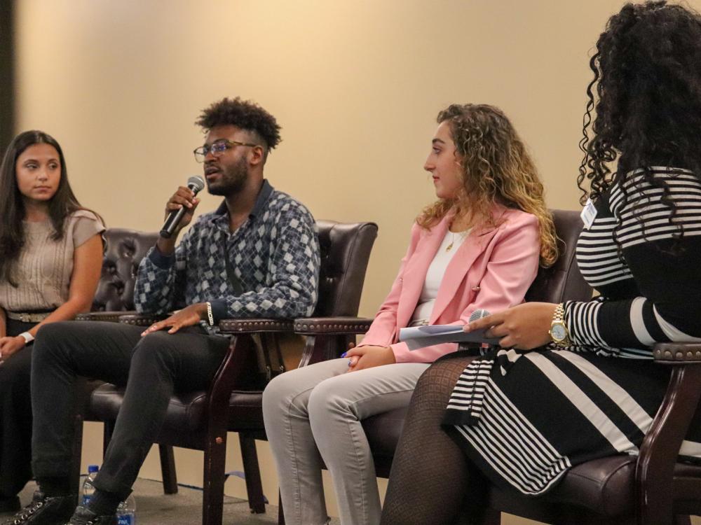 Three students on stage in panel setting