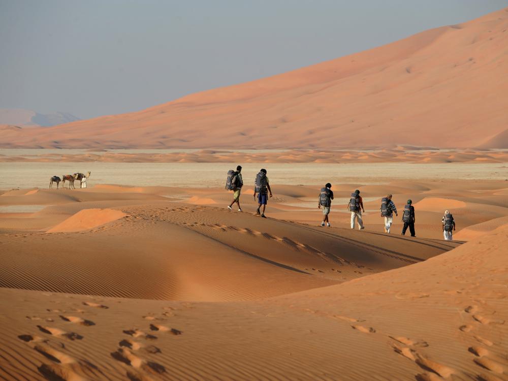 Outward Bound students walk across a desert wearing backpacks