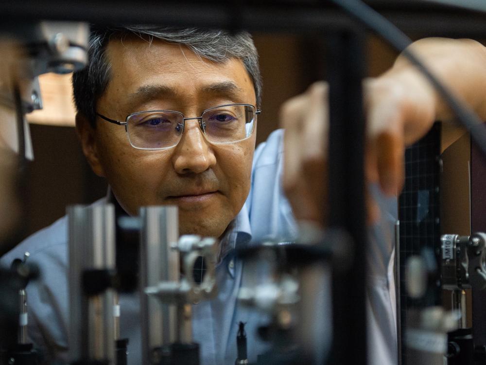 A person wearing glasses adjusts a component of a laser 