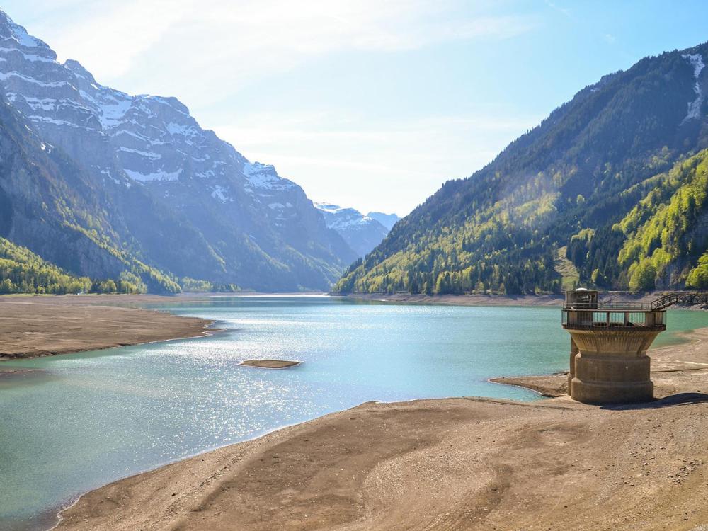 A reservoir with low water levels, with mountains in the background