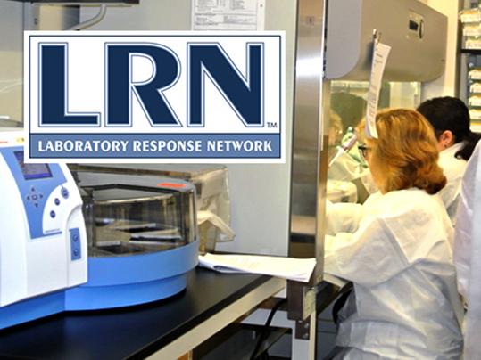 People in white labs coats working in a lab setting. The text "LRN Laboratory Response Network" is in the top left corner of the image.