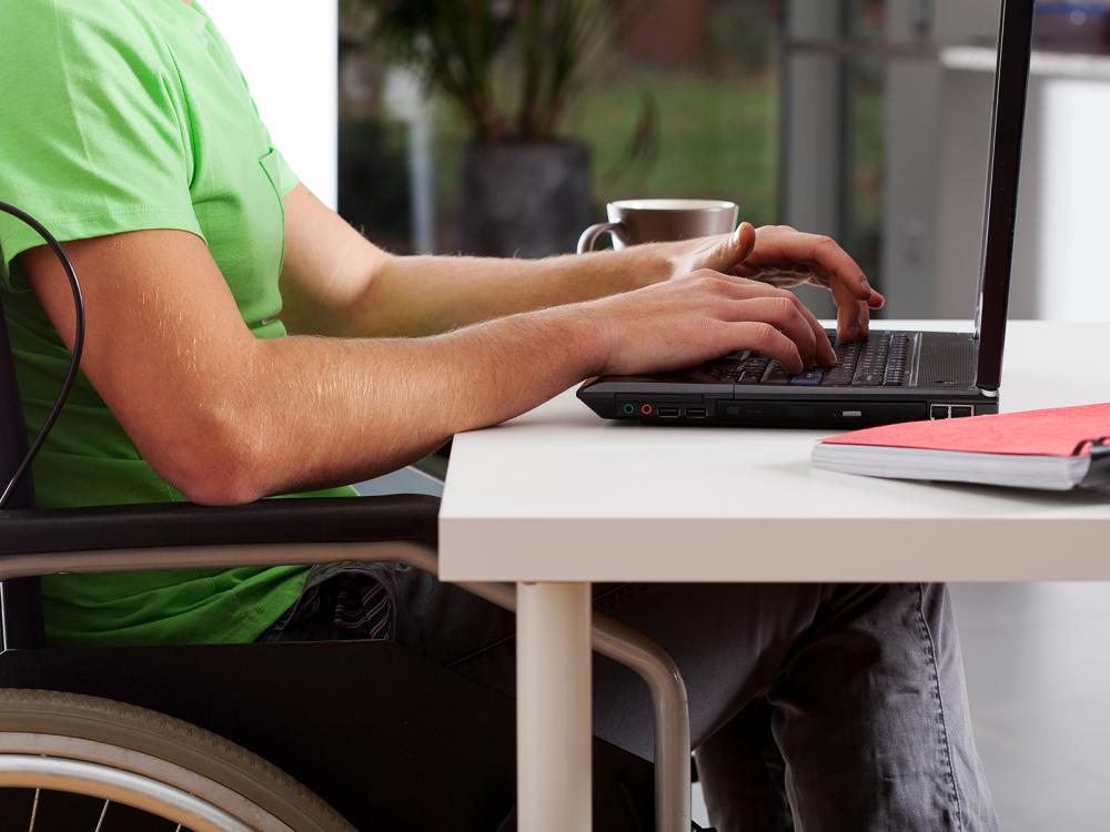 A man in a wheelchair uses a laptop