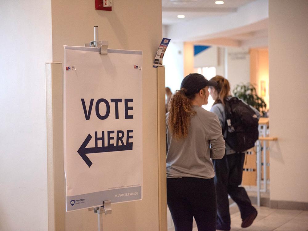 Vote Here sign in the HUB with students in background