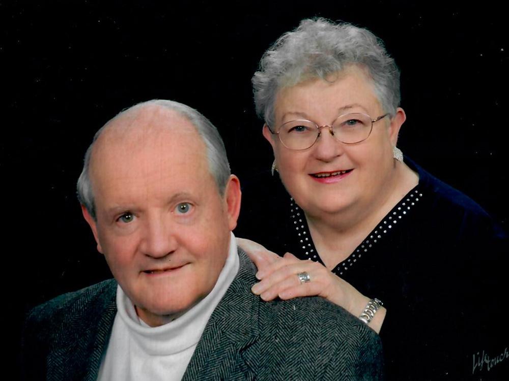 Two individuals pose in a formal headshot photo. 