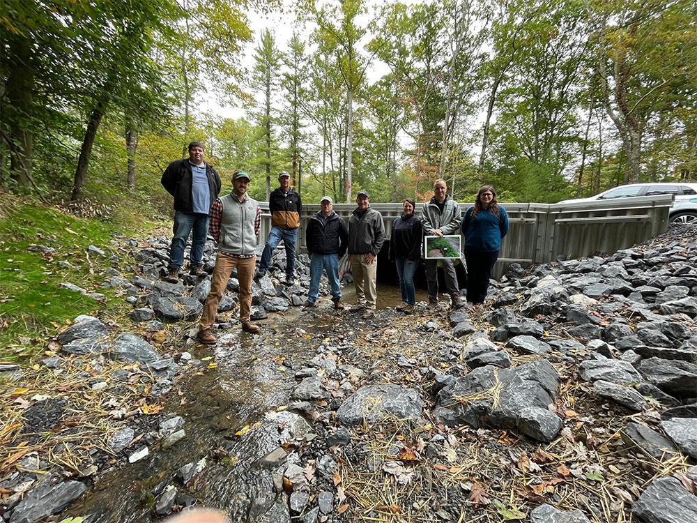 A group of people stand on a gravel road.