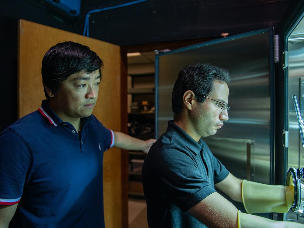 Two people calibrate a solar simulator-integrated thermal chamber in a lab.