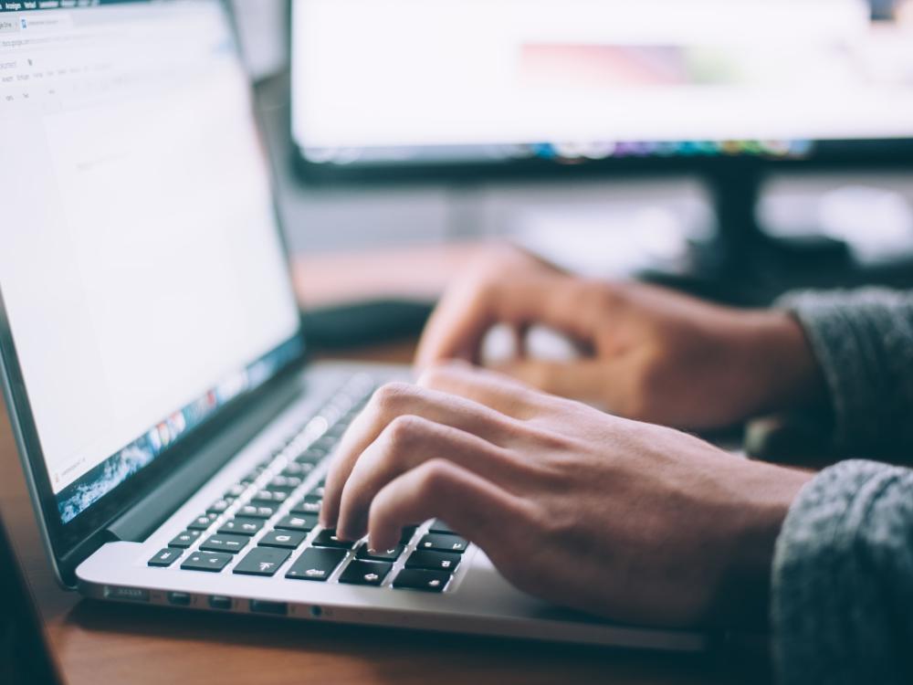 A person's hands typing on laptop computer