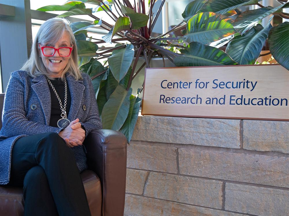 Lisa Witzig sitting next to sign for Center for Security Research and Education