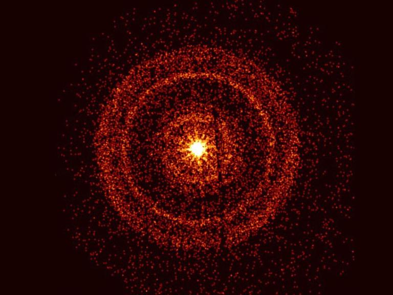 rings of red particles radiate outward from a bright yellow center