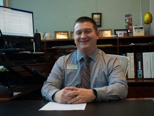 A man smiling behind a desk