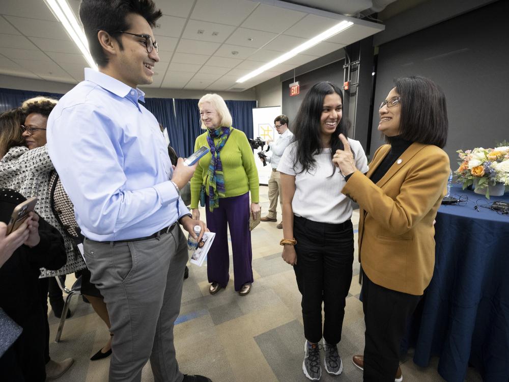 President Bendapudi chats with several students in a room.