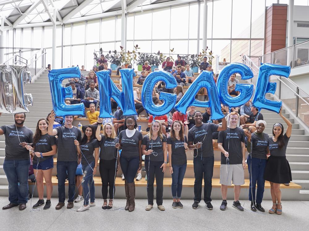 Students standing in hub with balloons that spell engage