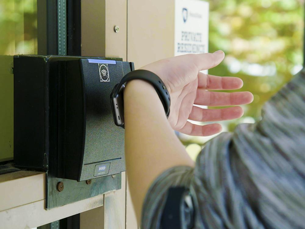 Student using Apple Watch to open door. 