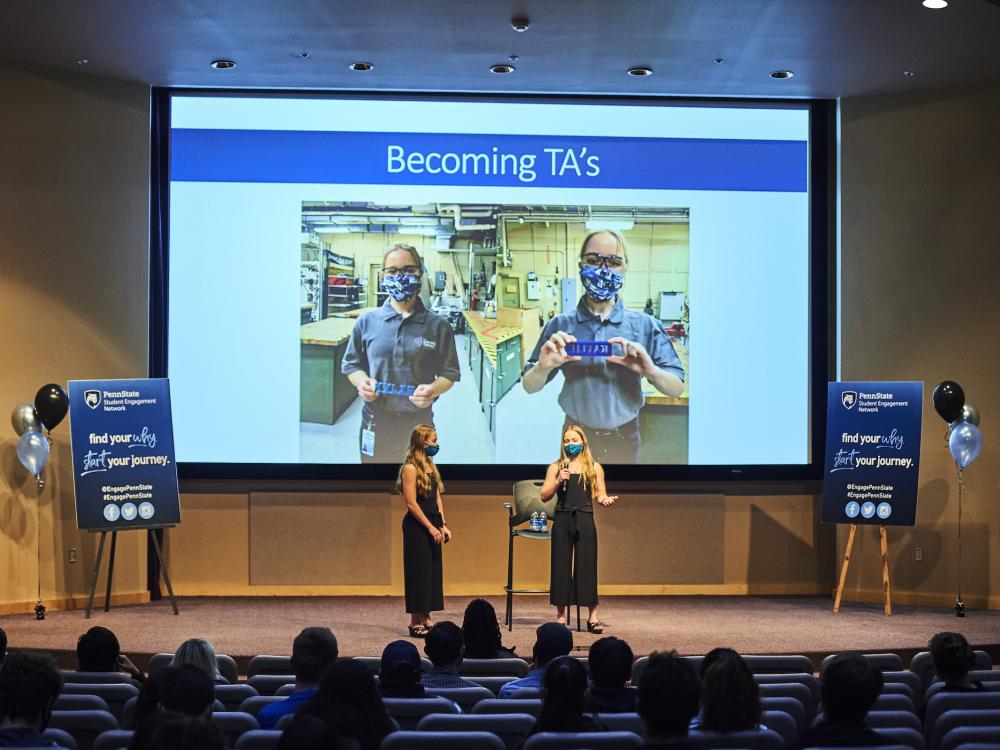 Two students present on a stage to audience