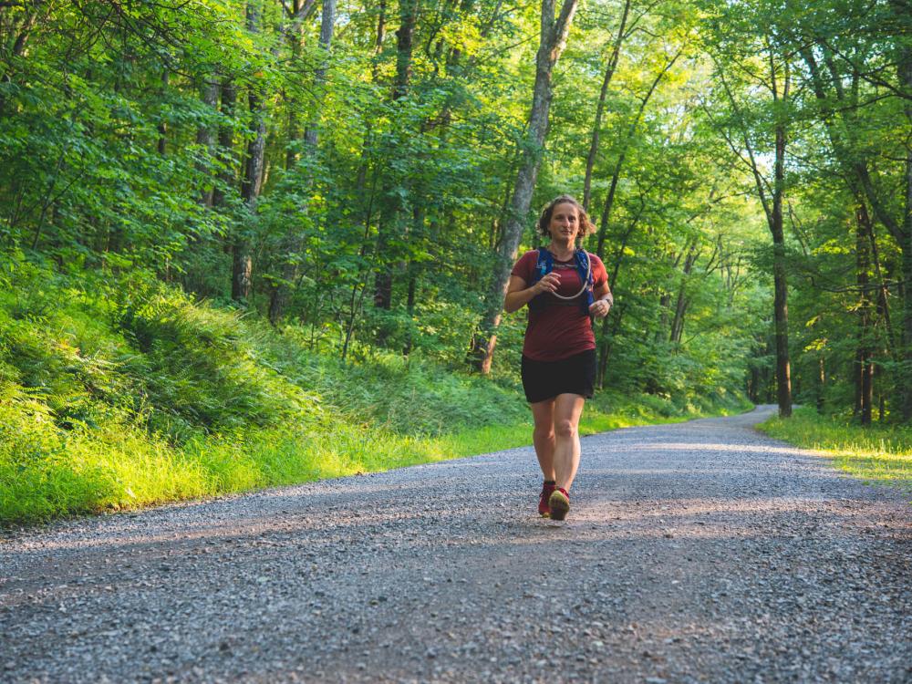 Tracy Langkilde, dean of the Eberly College of Science and a dedicated trail runner, jogs down a gravel lane lined by greenery
