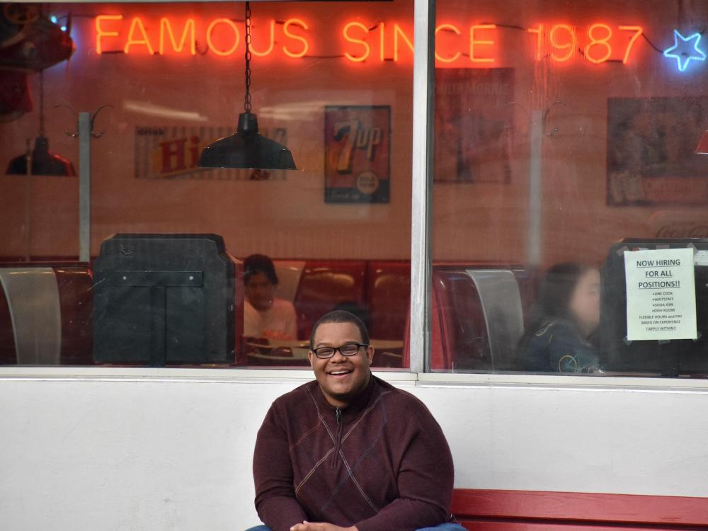 Photograph of man posing in front of diner