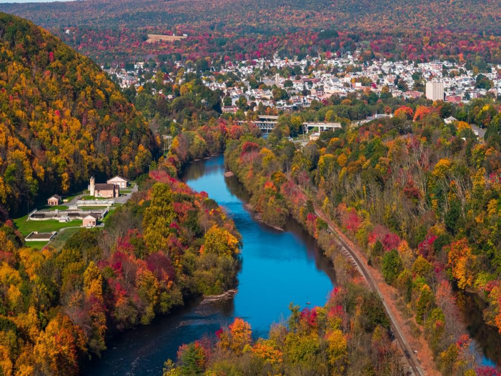 An image of a rural community tucked alongside a river and surrounded by trees. 