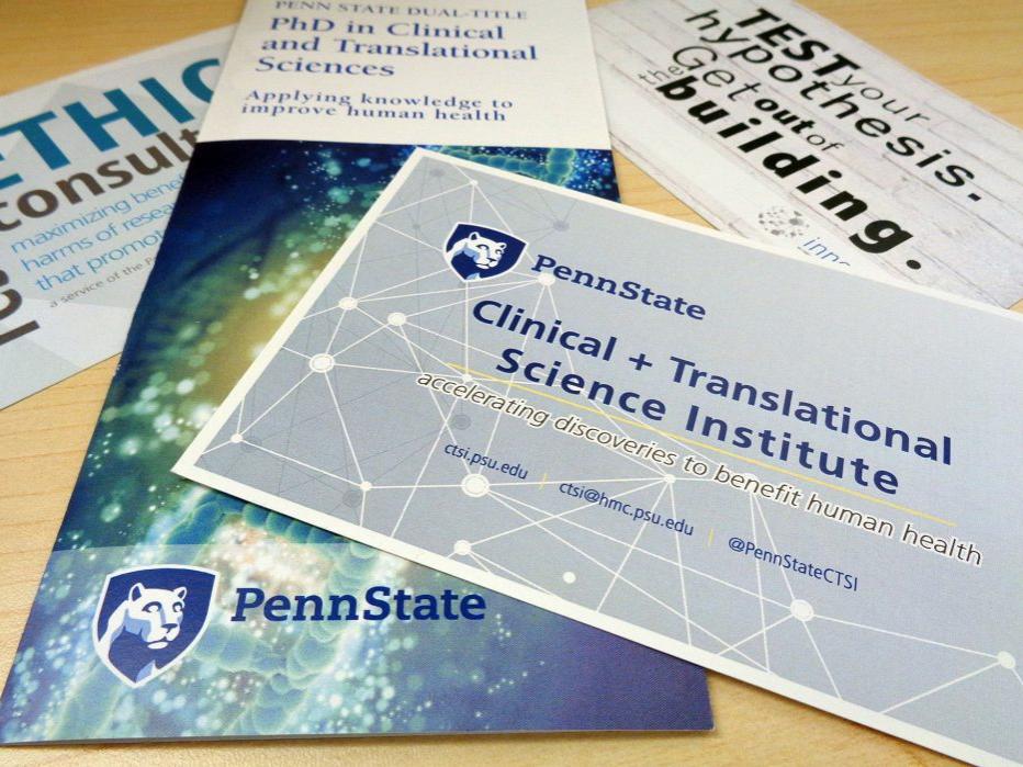 A pile of brochures advertising Penn State Clinical and Translational Science resources lays on a desk. 