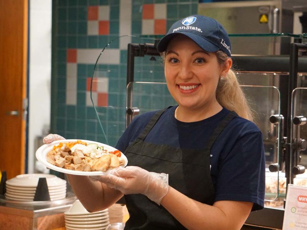 Female Housing and Food Services worker holding a plate of food.