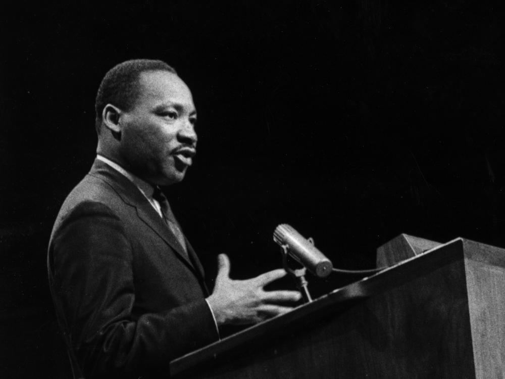 A black and white image of Martin Luther King speaking at a podium