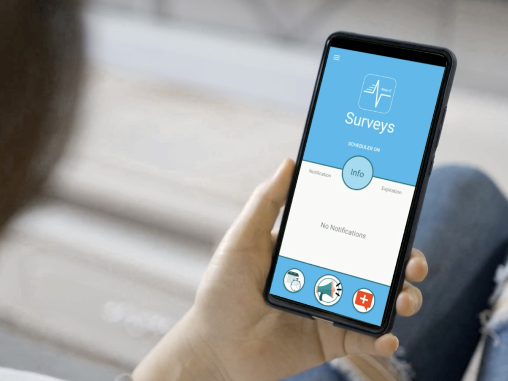 Woman holding a smart phone in her hand, showing a survey screen from the WearIT app