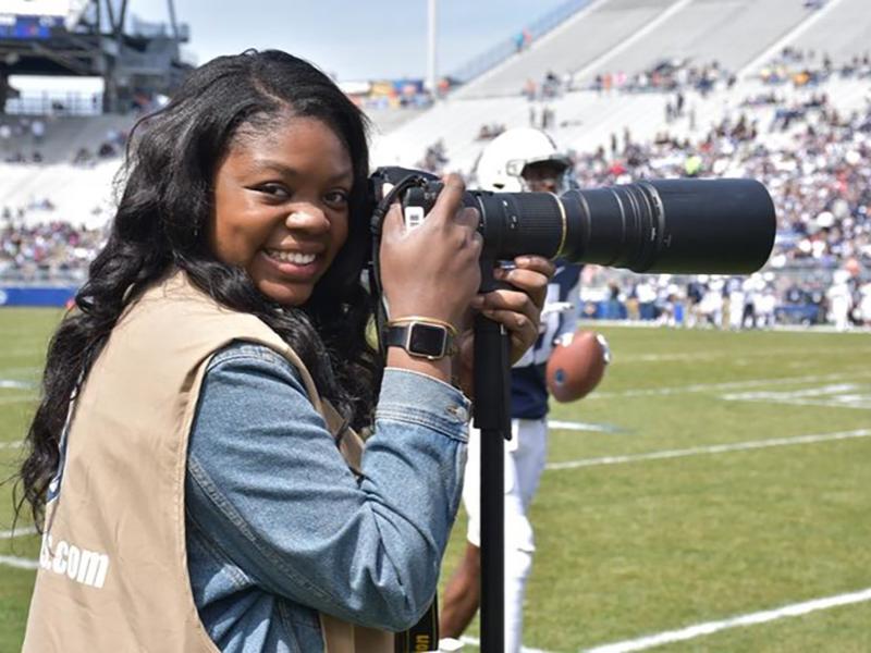 Adriana Lacy holding a camera while on the sideline at a football game