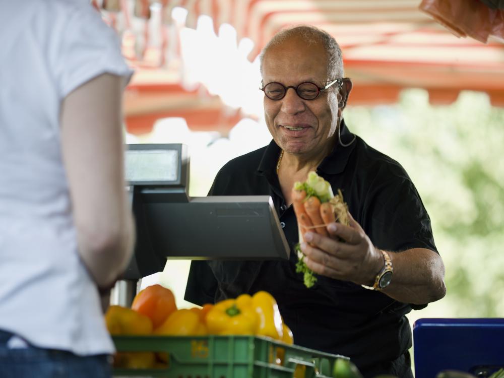 Older man buying carrots at a farmers market 