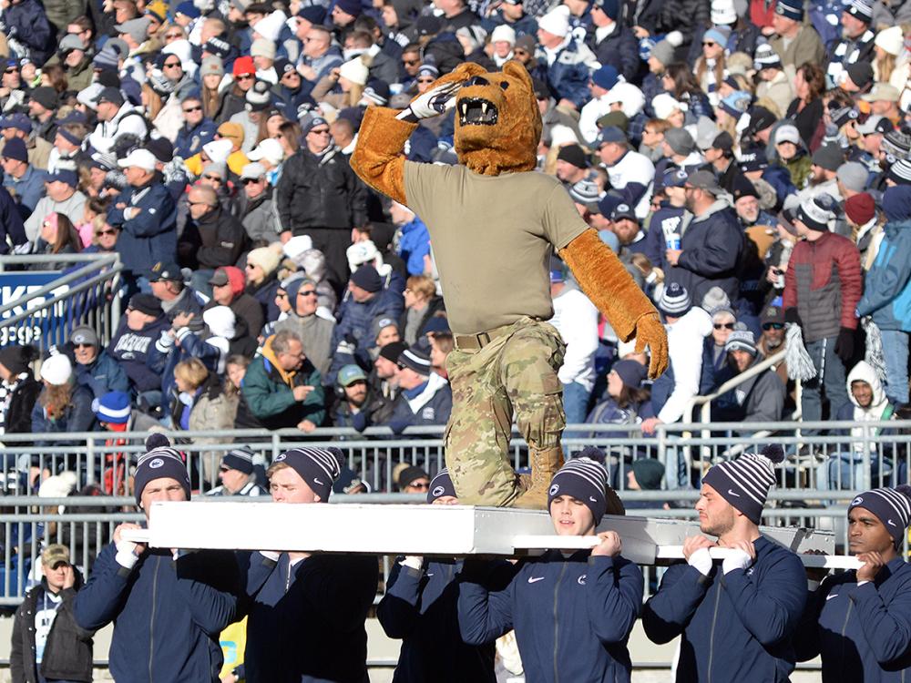 Nittany Lion saluting while being held up on stand