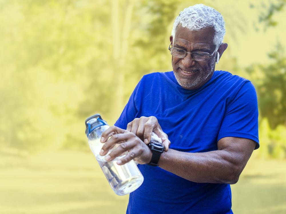 Older man holding a water bottle and checking his smartwatch