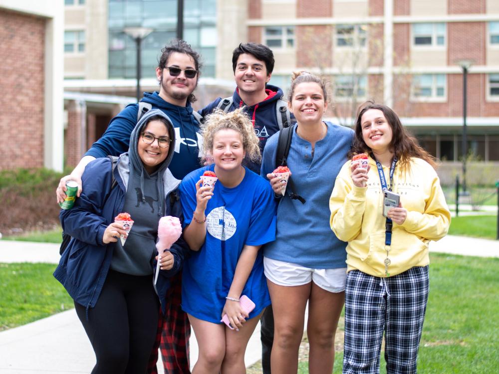 Students pose together with treats at a Residence Life carnival on campus.