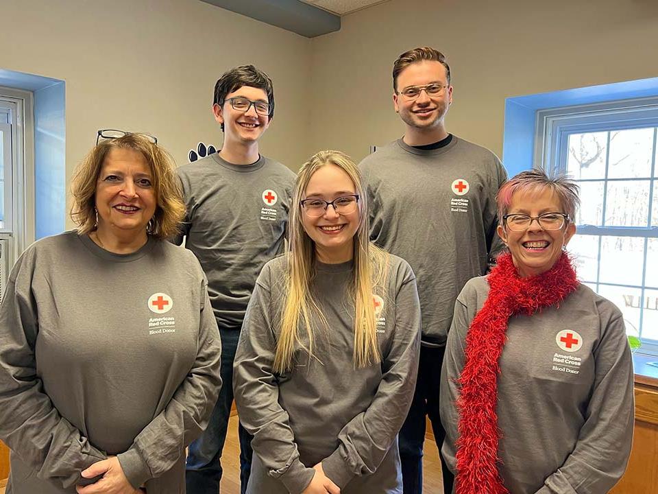 A group of people standing together wearing Red Cross T-shirts