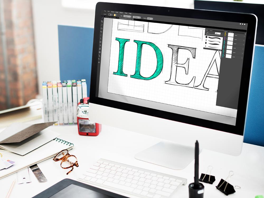 Image of a laptop with someone designing a logo of the word idea