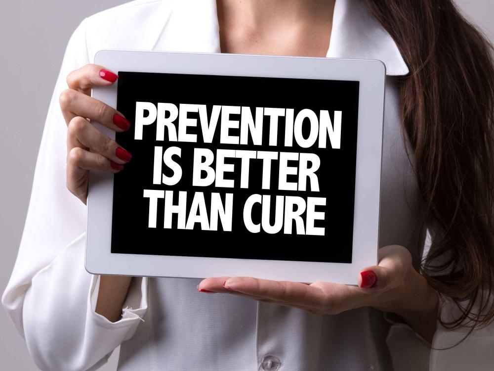 woman holding sign that says, prevention is better than cure