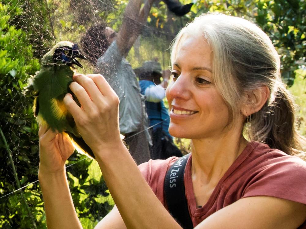 Woman looking at colorful bird in net