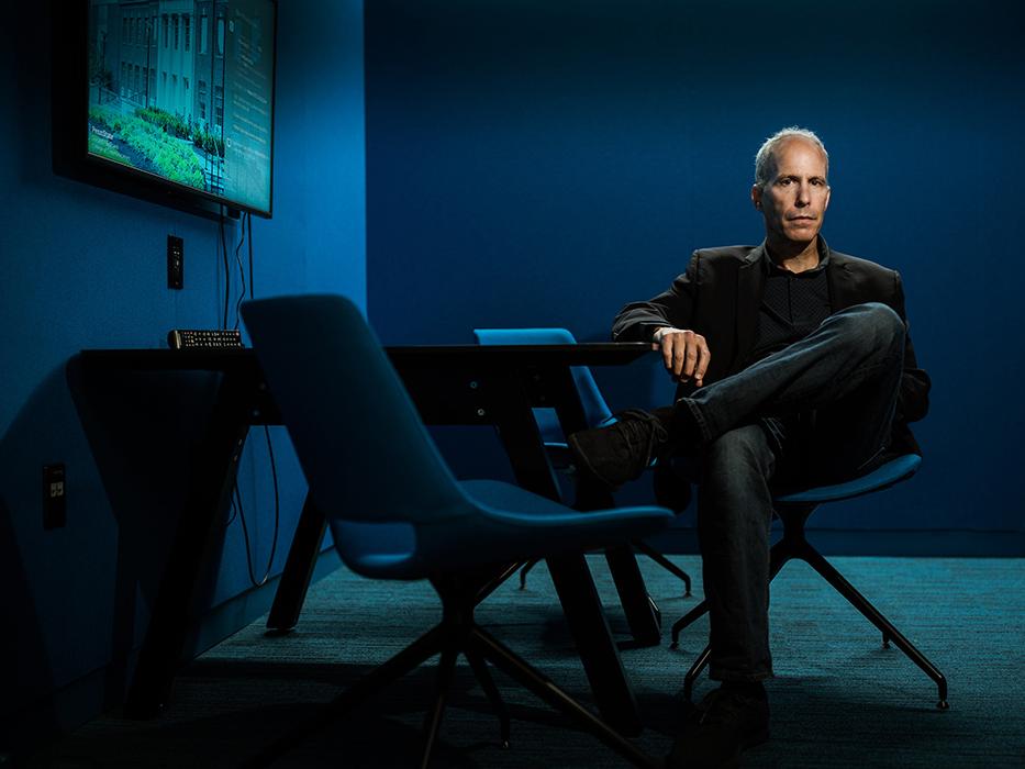 Faculty member seated, legs crossed in chair