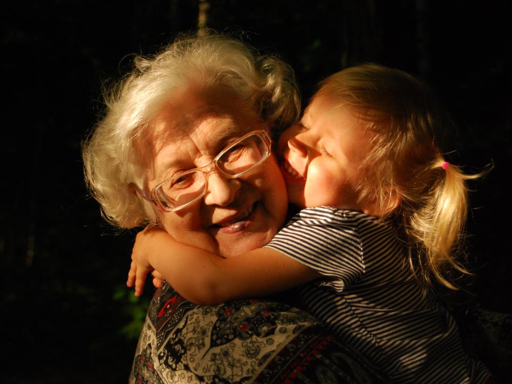 A young girl hugging her grandmother while they both smile