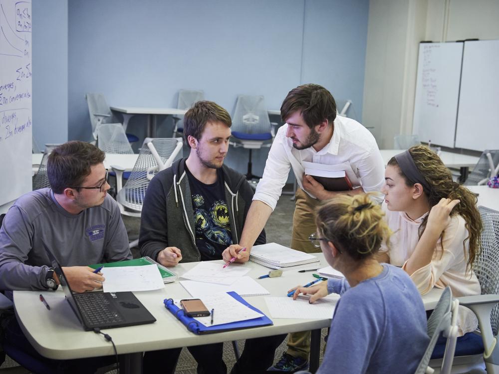 Students working at table with a guided study group leader