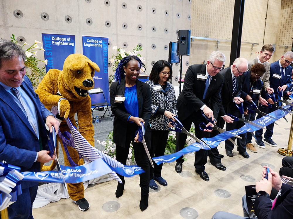 nine people cut a ribbon at a ribbon-cutting ceremony for a new building