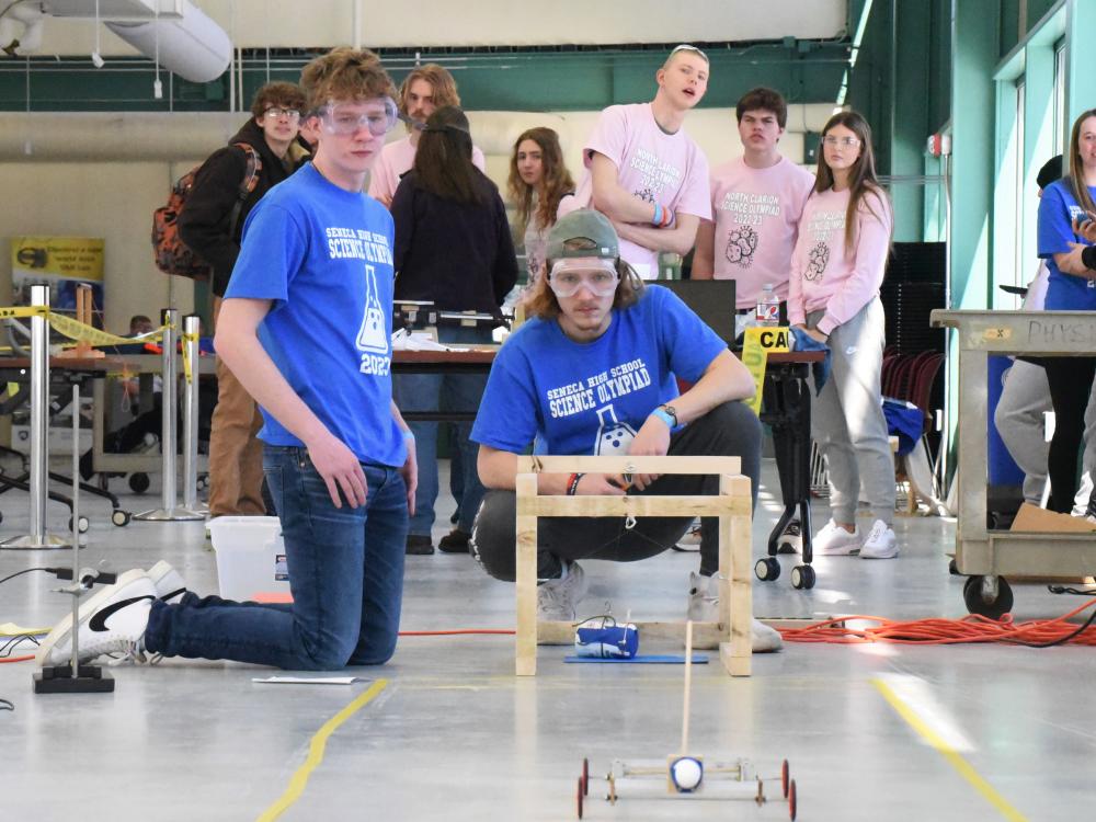 Two students watch as a model car is pushed down a test zone at Penn State Behrend's Science Olympiad.