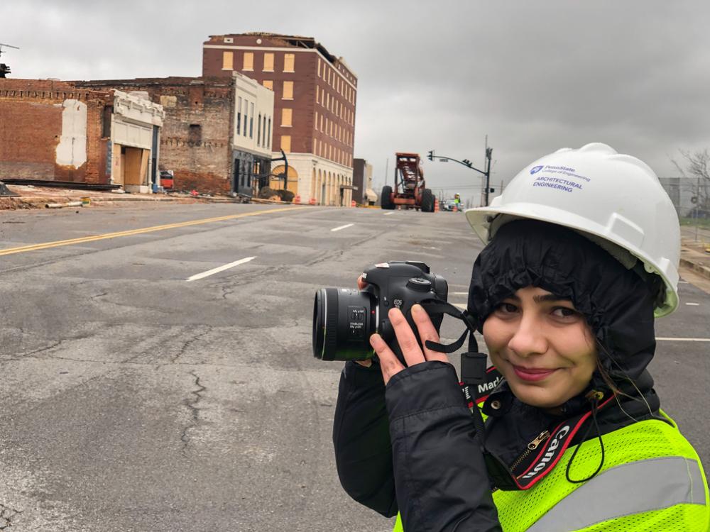 An individual wearing a hard hat holds a camera